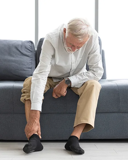 An older adult easing foot pain from peripheral neuropathy
